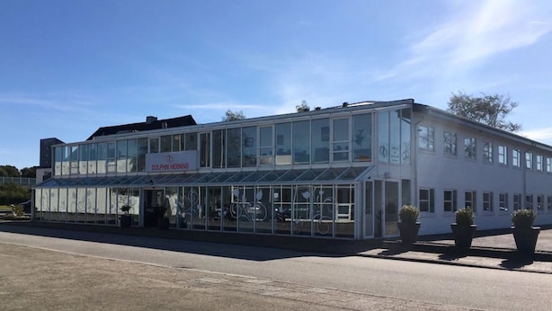 A two-story building with a glass facade and a sign reading "Dolphin Herning." - Dolphin Hotel Herning (Herning)