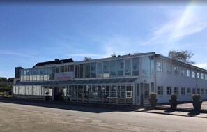 Un bâtiment à deux étages doté d’une façade en verre et d’une enseigne indiquant « Dolphin Herning ».