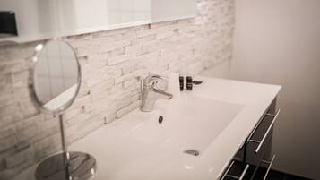 Une salle de bain avec un lavabo blanc, un miroir rond et un robinet moderne.
