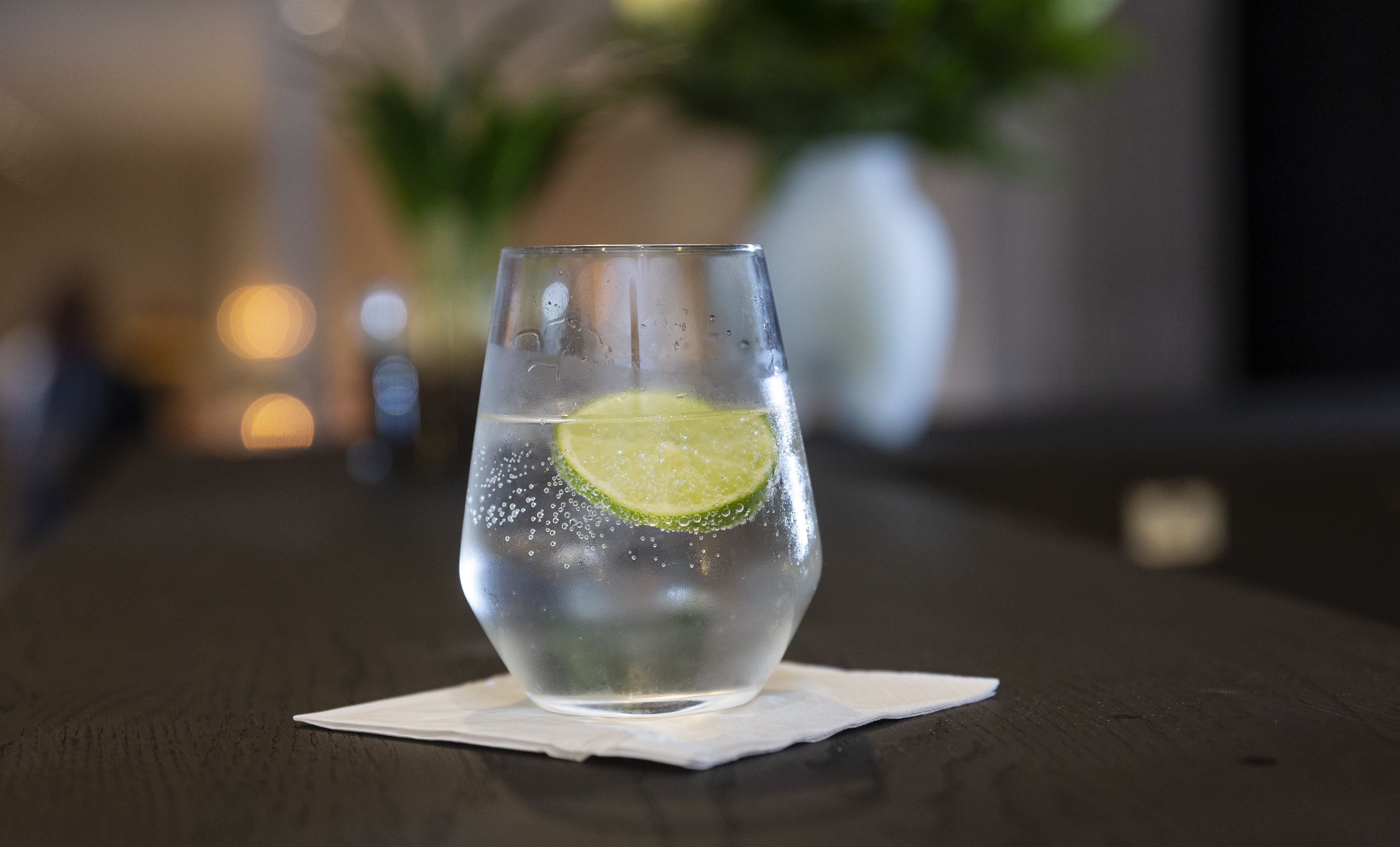 A clear glass with a lime slice on a wooden table.