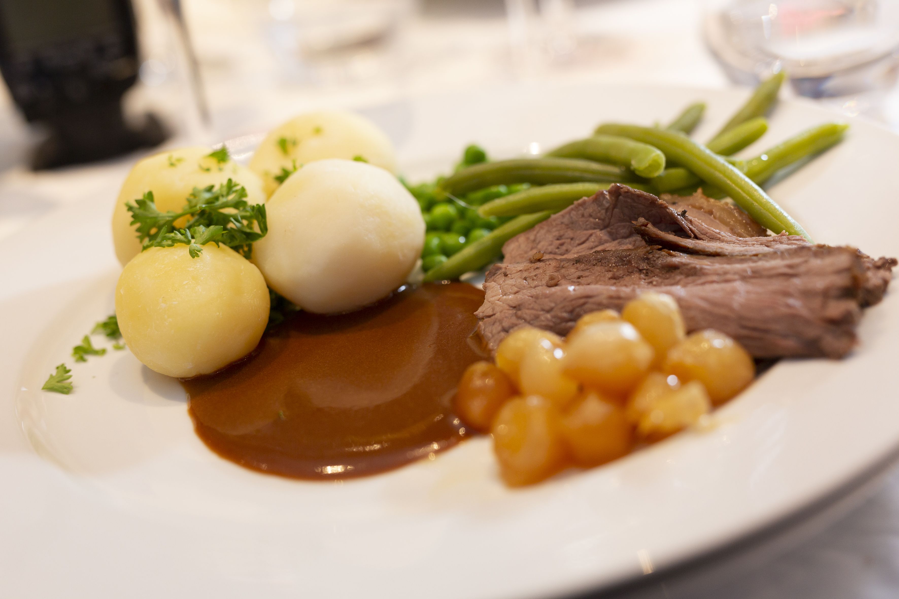 A plate with beef, green beans, potatoes, and a sauce.