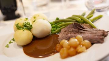 A plate with beef, green beans, potatoes, and a sauce.