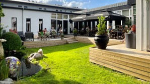 A courtyard with outdoor seating, a garden, and a building with large windows. - Dolphin Hotel Herning (Herning)