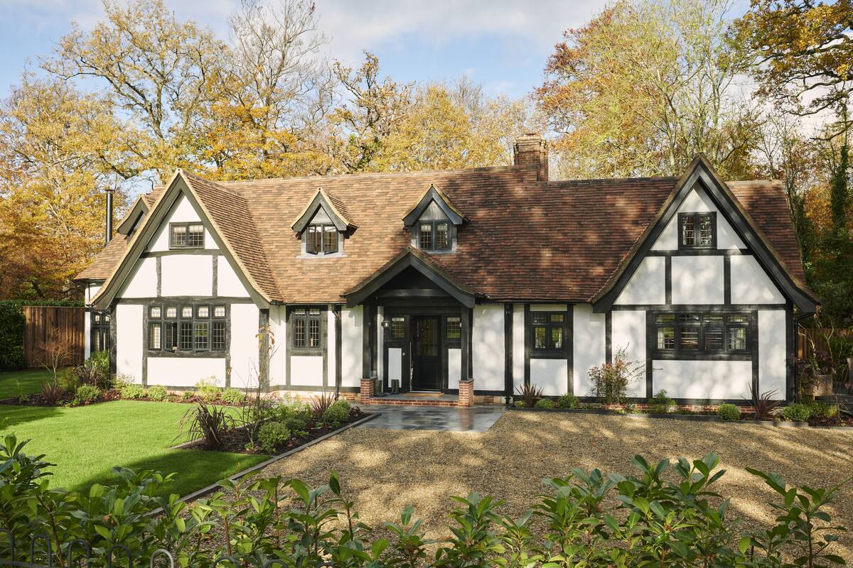 A traditional half-timbered house with a symmetrical facade, a central entrance, and a well-maintained garden.
