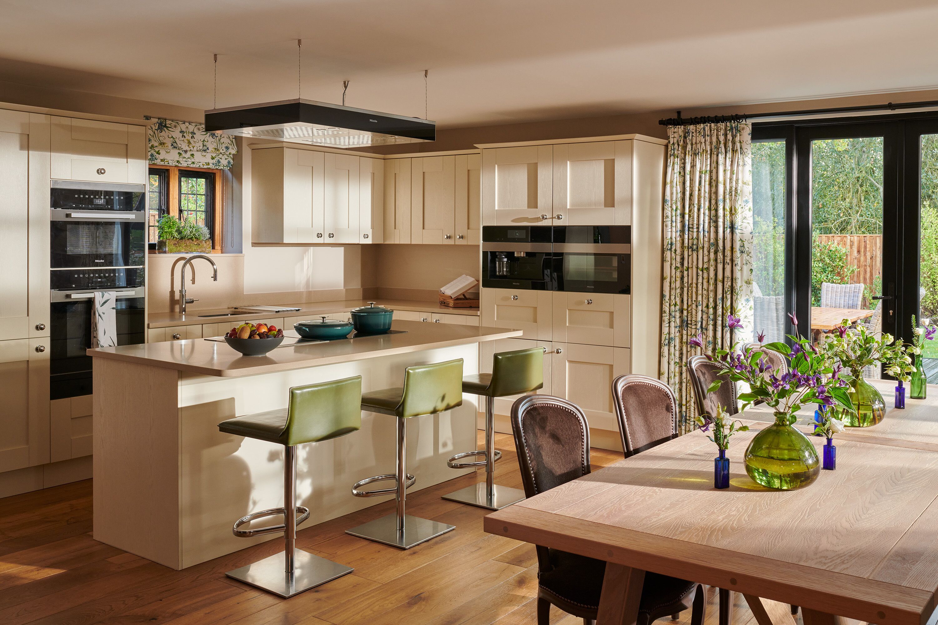 A modern kitchen with an island, bar stools, and a dining table with chairs.