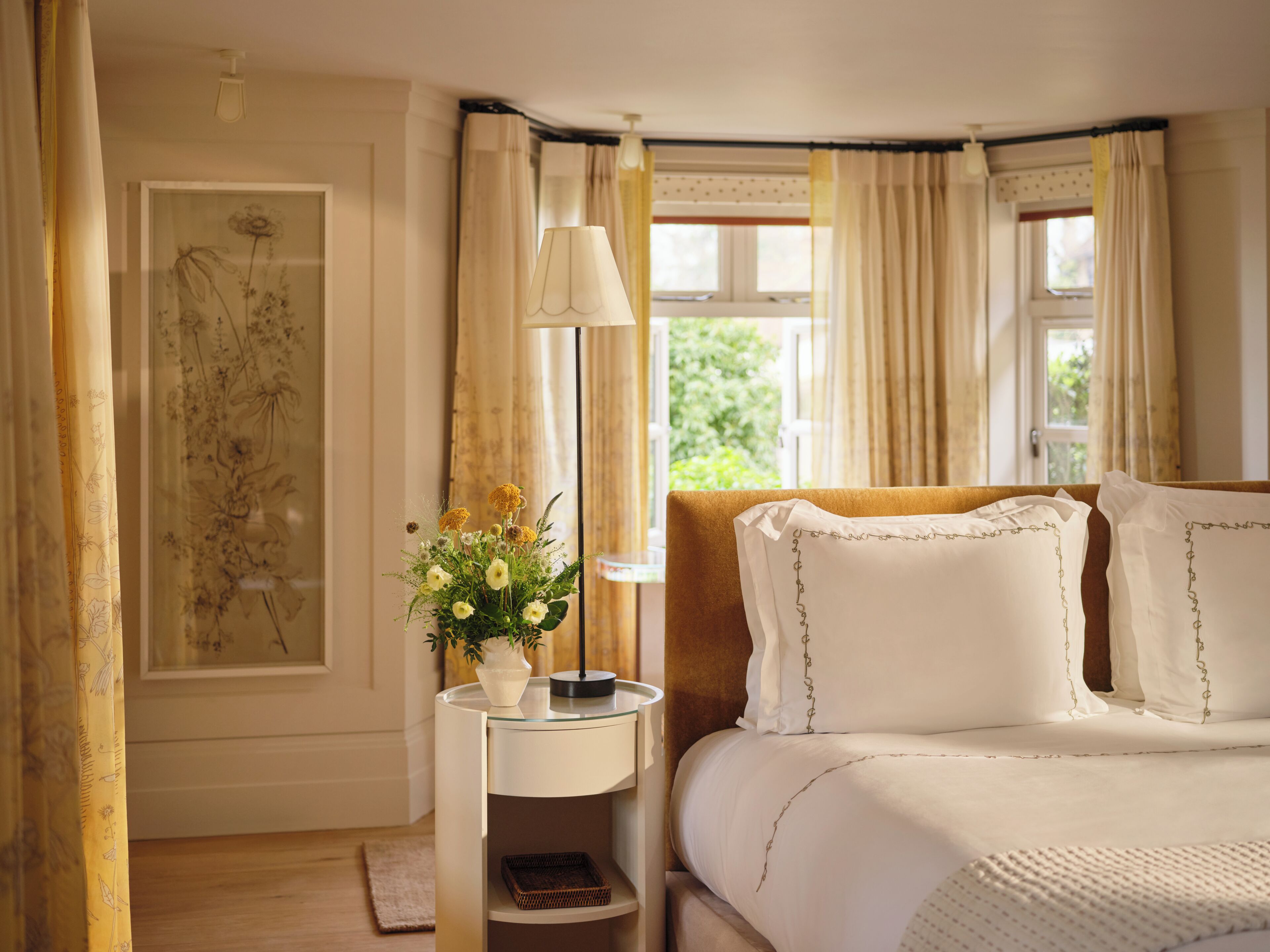A bedroom with a bed, bedside table, lamp, and a window with curtains.