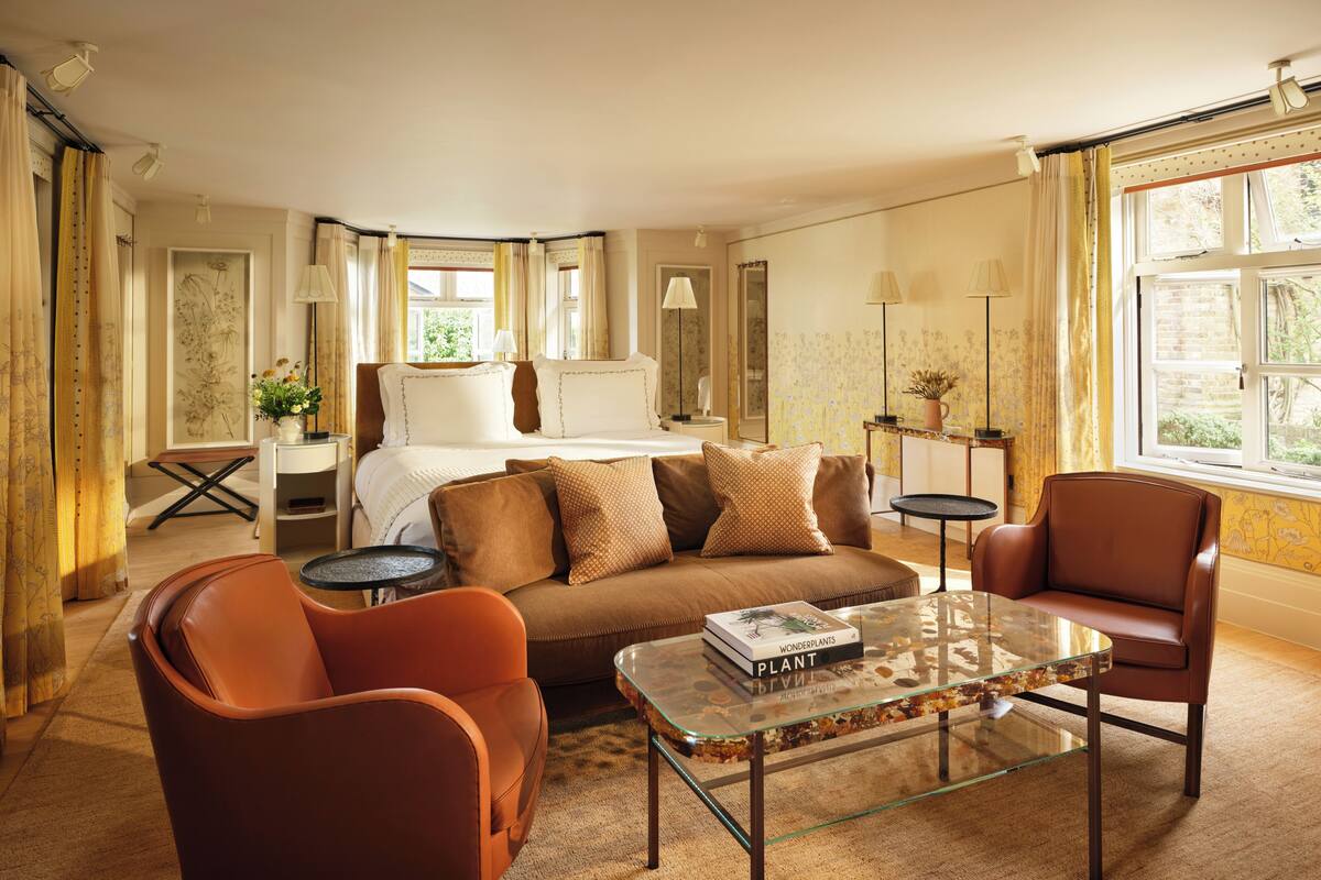 A hotel room with a bed, a sofa, a coffee table, and a chair.