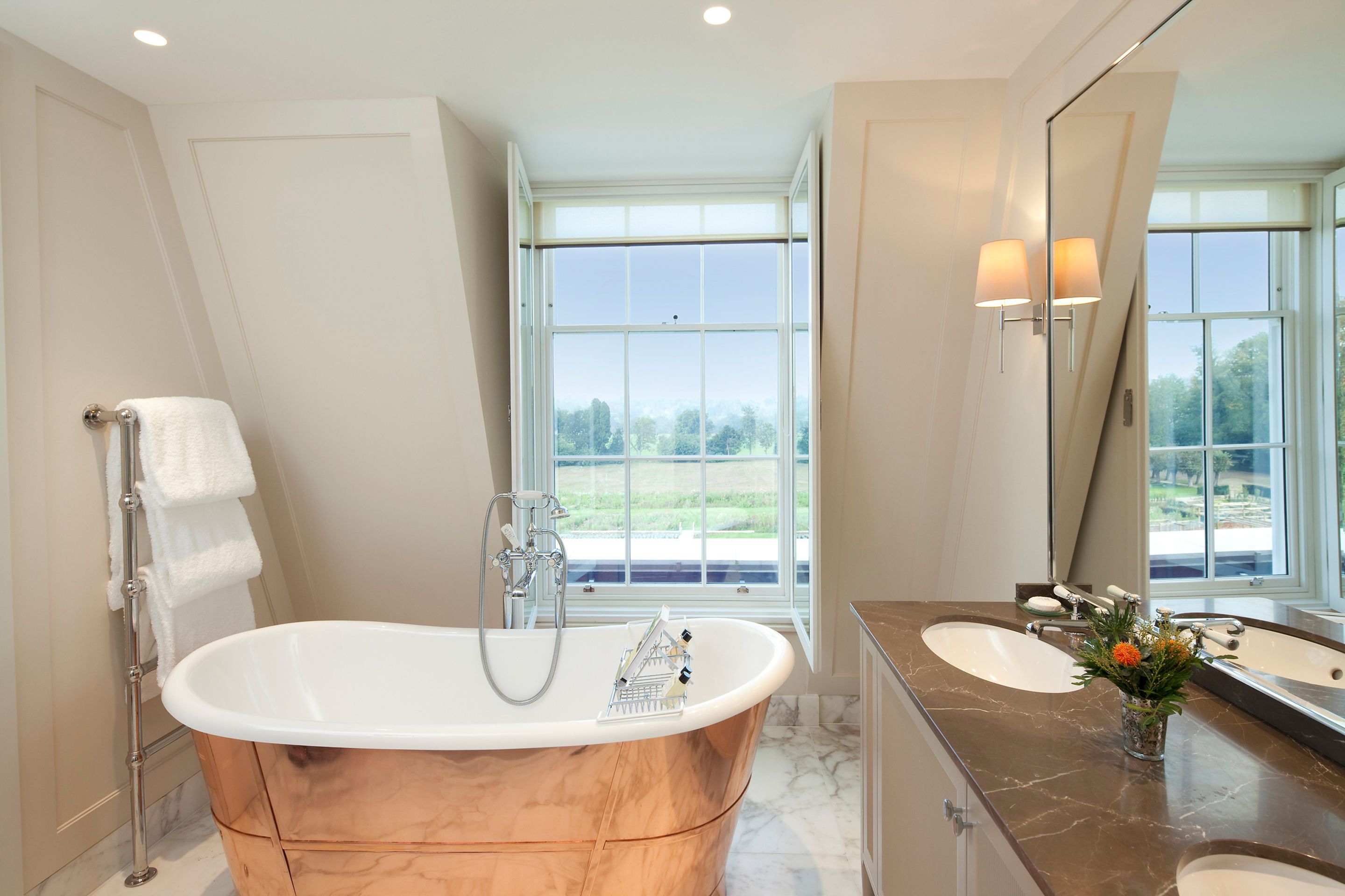 A modern bathroom with a freestanding bathtub, two sinks, and a large mirror.