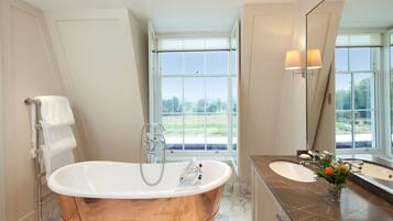 A modern bathroom with a freestanding bathtub, two sinks, and a large mirror.