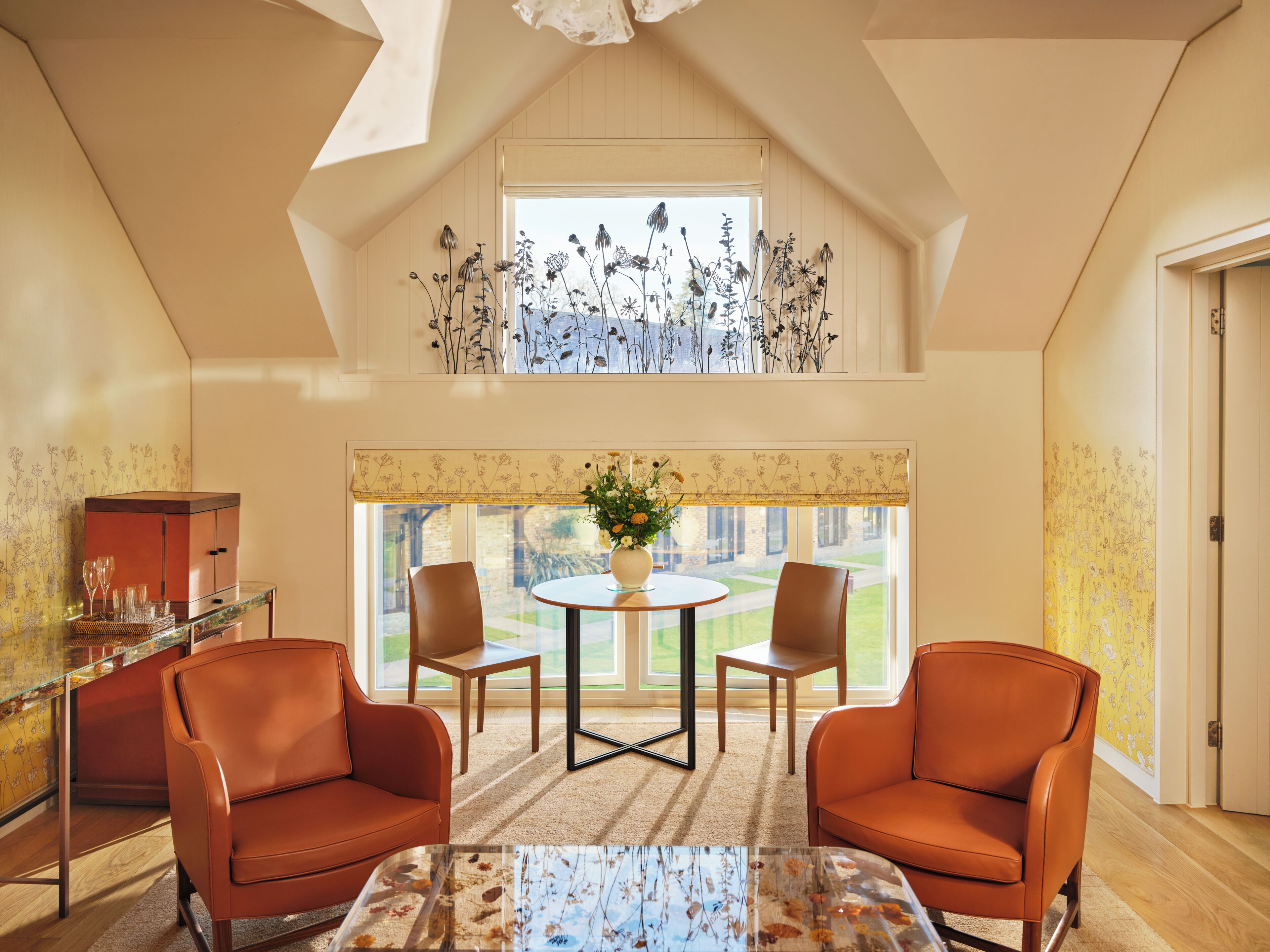 A room with a high ceiling, a dining table with chairs, a sofa, and a decorative vase.