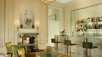 A bar area with a glass counter, multiple stools, and a variety of bottles and glasses.