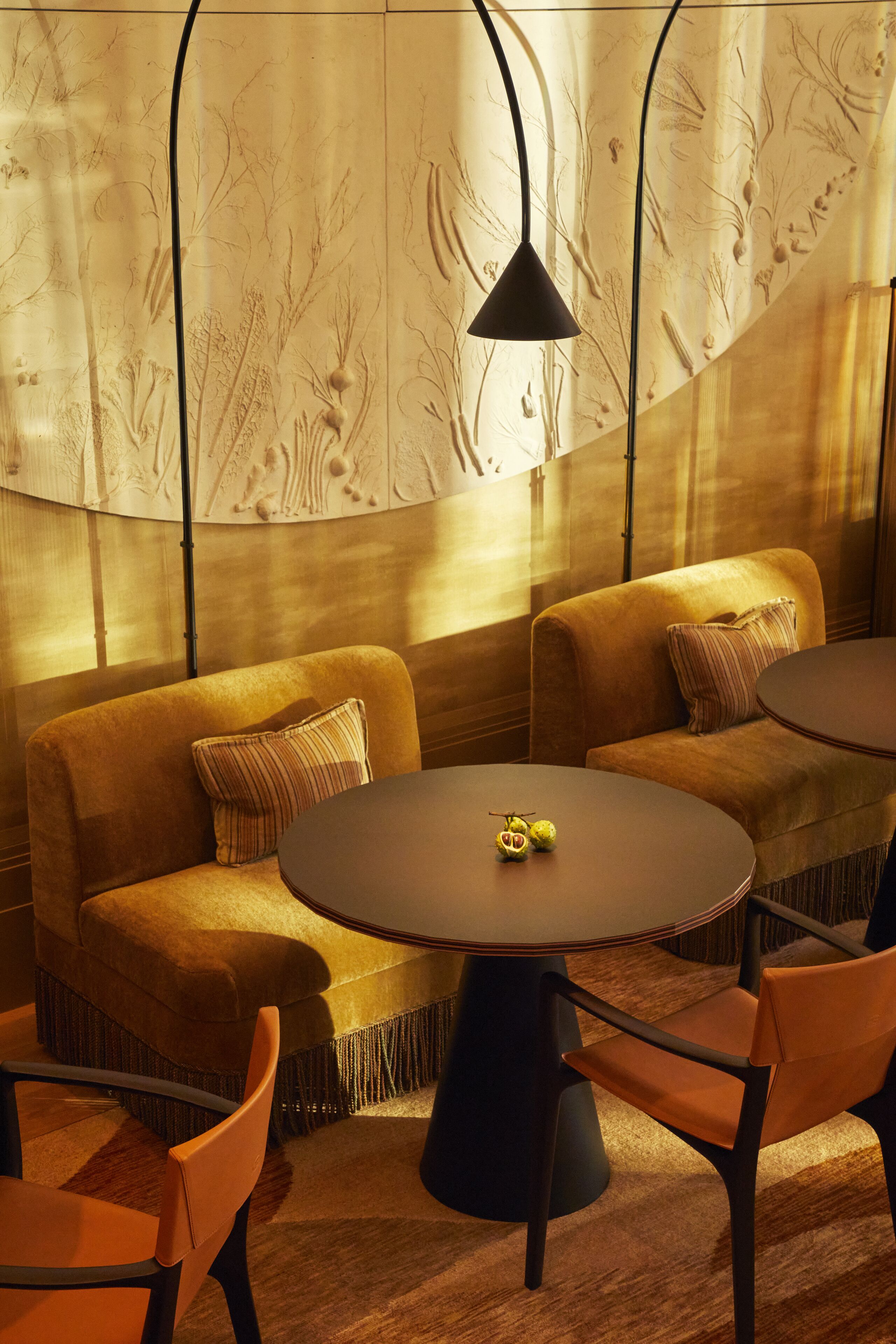 A cozy seating area with a round table, cushioned sofas, and a hanging lamp.