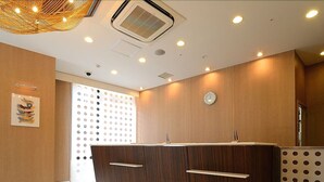 A modern reception area with a wooden reception desk, a wall-mounted clock, and a decorative wall panel. - Ginza International Hotel (Tokyo)