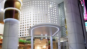 A modern building entrance with a glass facade, a red carpet, and a circular design with holes. - Ginza International Hotel (Tokyo)