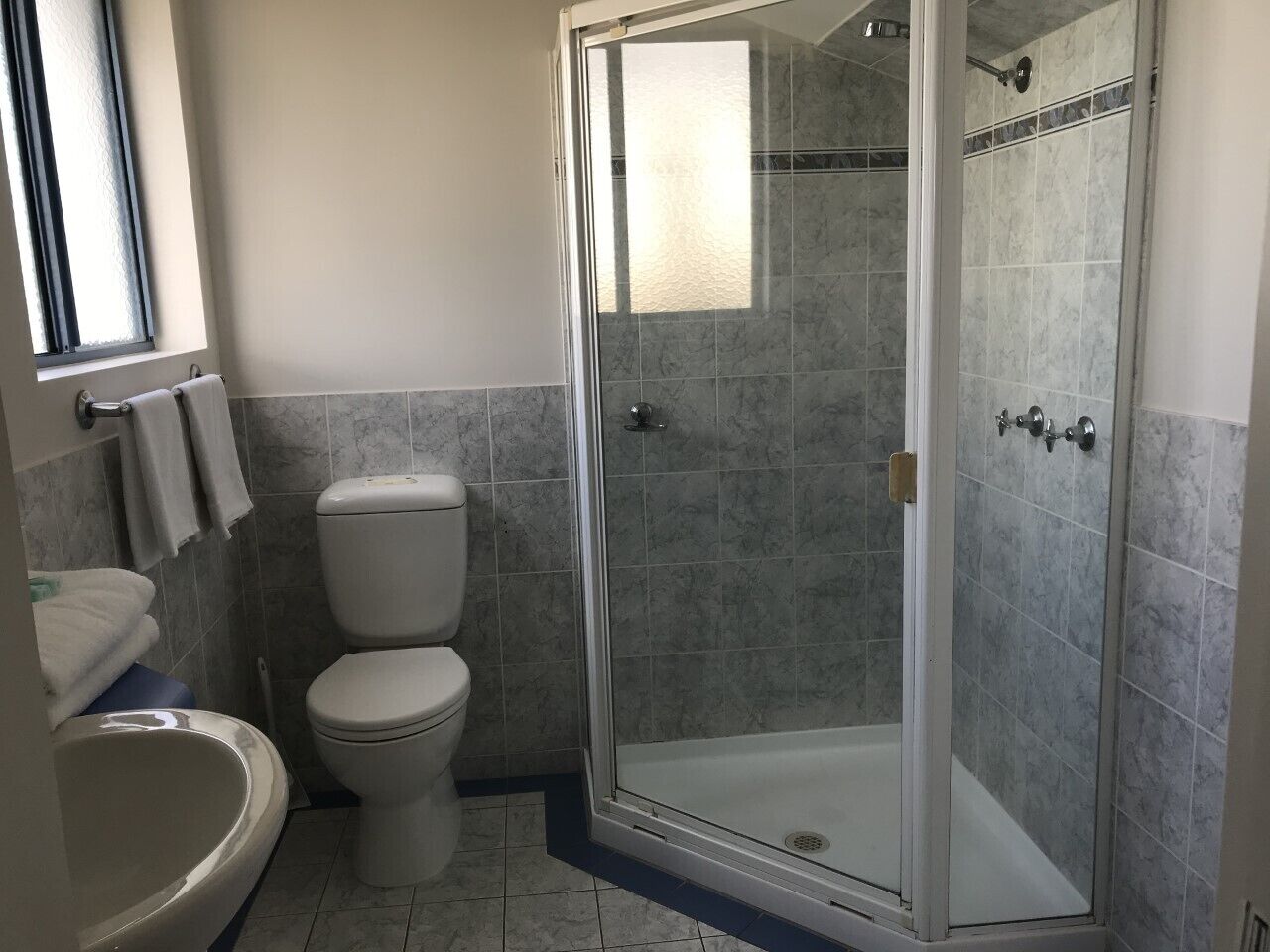 Een badkamer met toilet, wastafel en douchecabine.