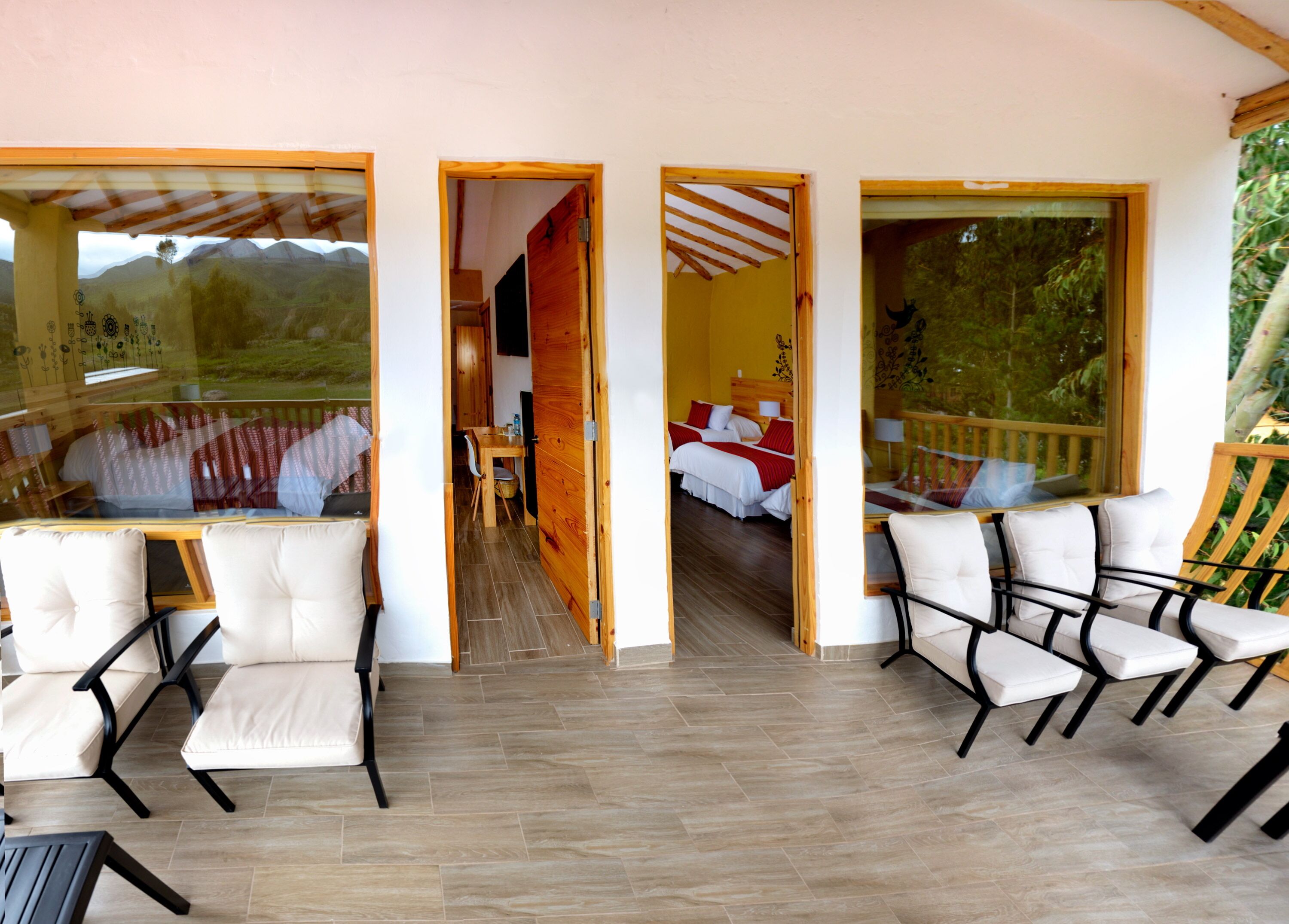 A hotel room with a bed, a desk, and a view of the outdoors. There are chairs and a table in the room.