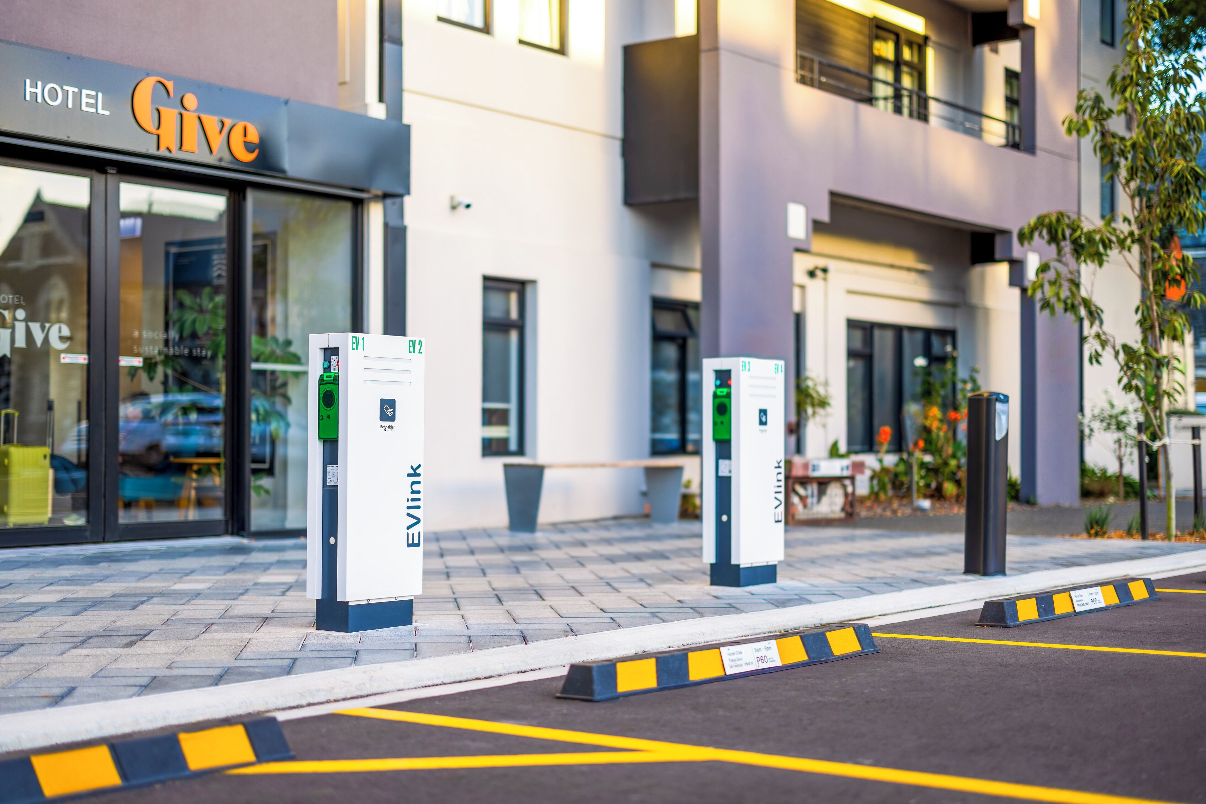 Een hotelingang met laadpalen voor elektrische auto's en een duidelijke parkeerroute.