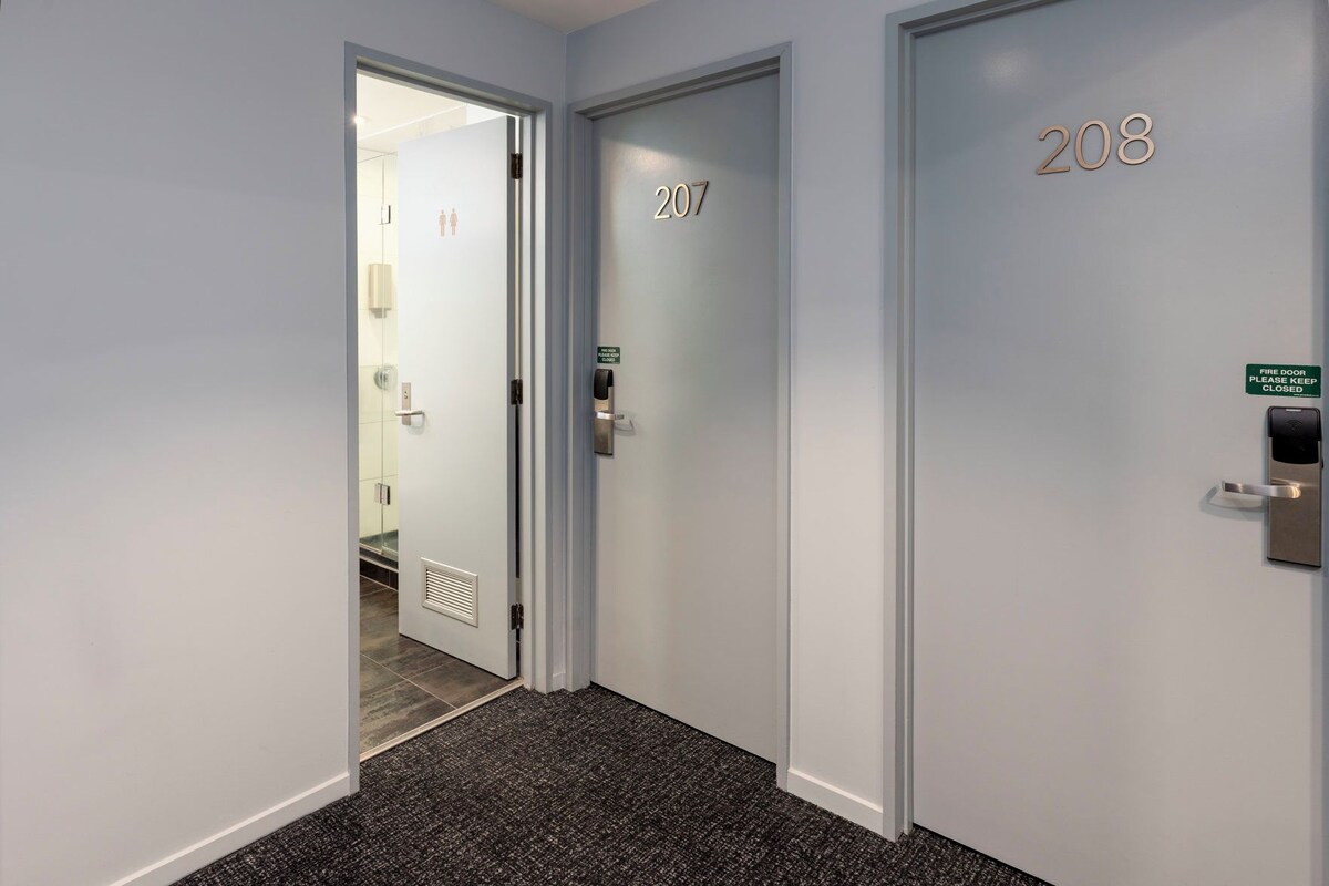 A hallway with doors numbered 207 and 208, a fire door sign, and a keycard reader.