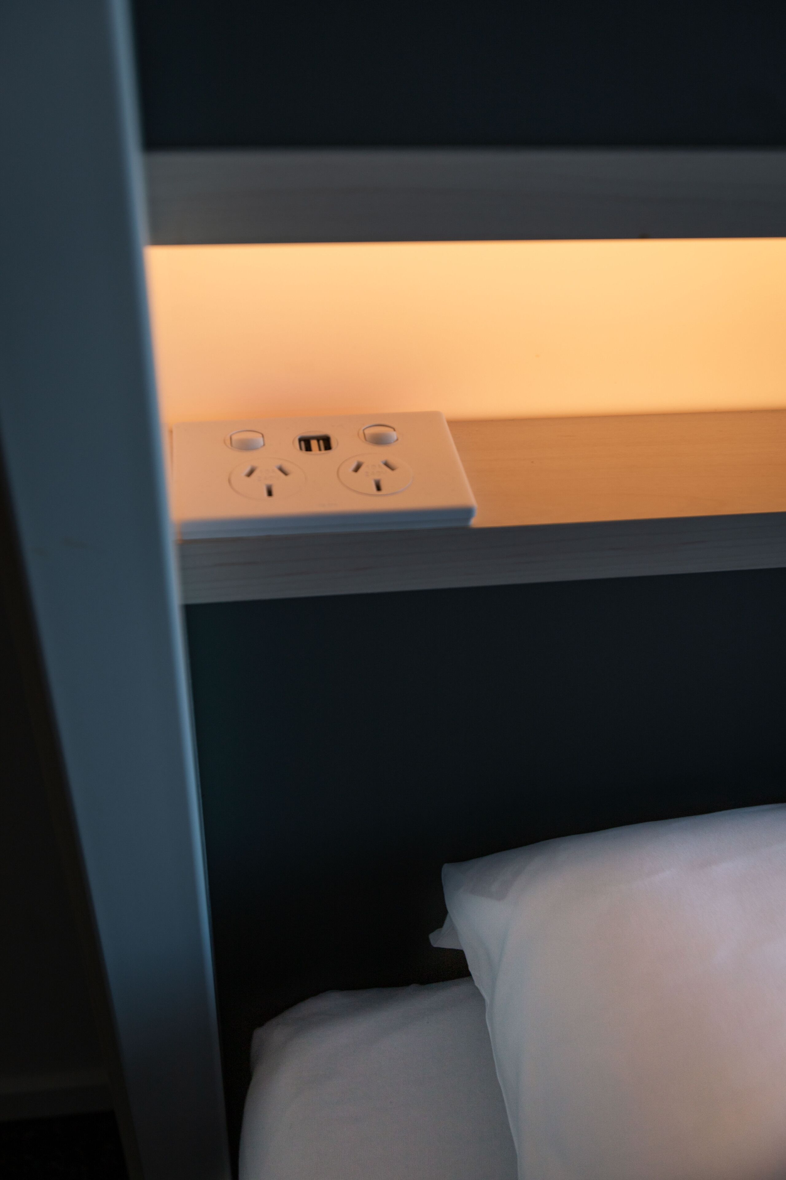 A bunk bed with a bedside table and a power outlet.