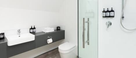 A modern bathroom with a white sink, black countertop, and a glass-enclosed shower area.