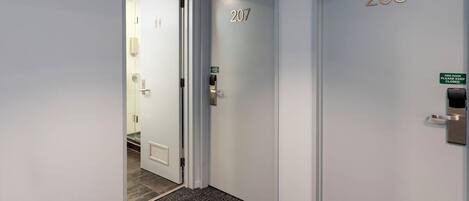 A hallway with two doors, one labeled 207 and the other 208, both with a fire door intercom system.