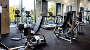 A gym with treadmills, weight machines, and a large window offering a view of the outdoors. - Hotel Give (Christchurch)