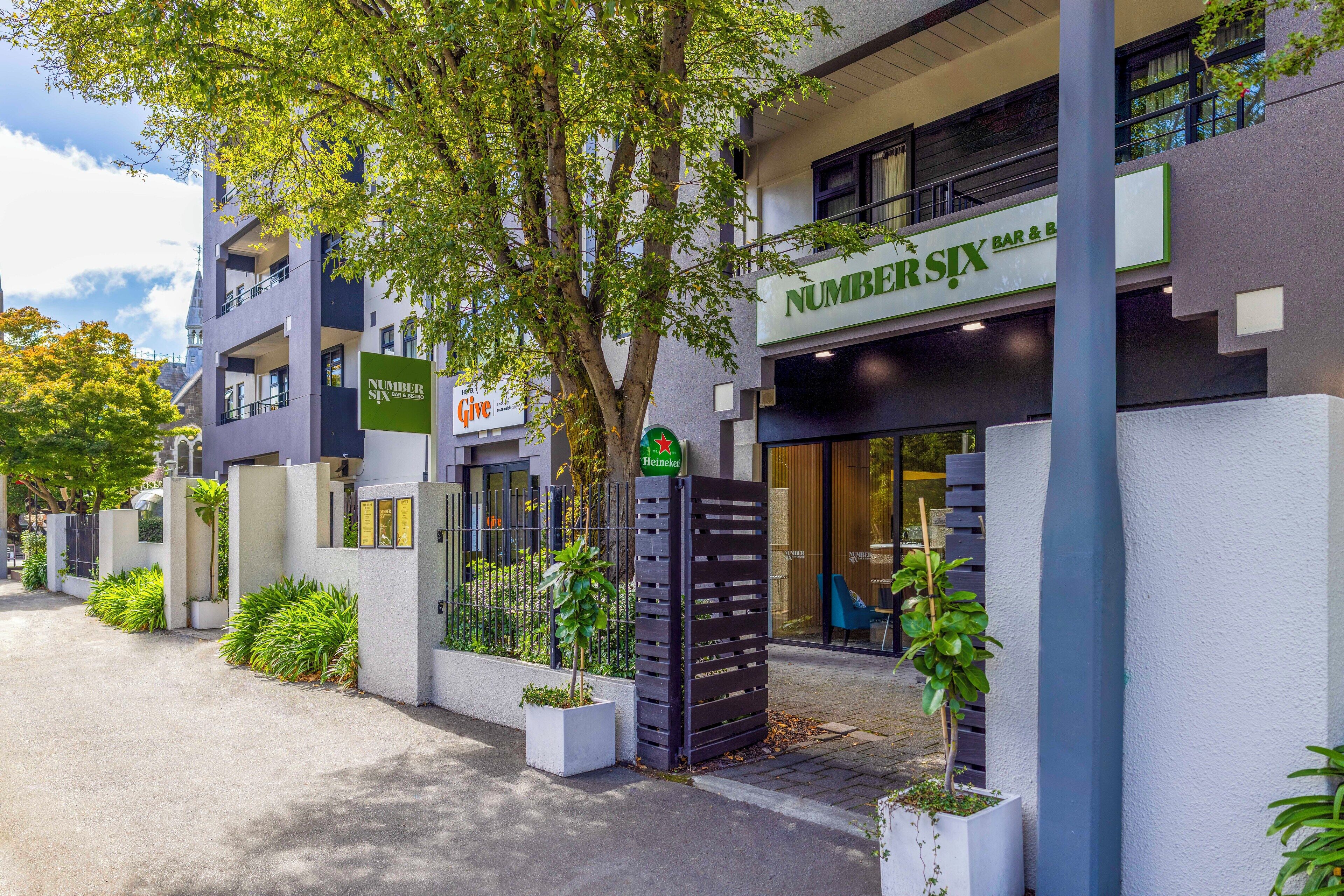 A modern building with a bar named 'NUMBERSIX' and a 'Give' sign.