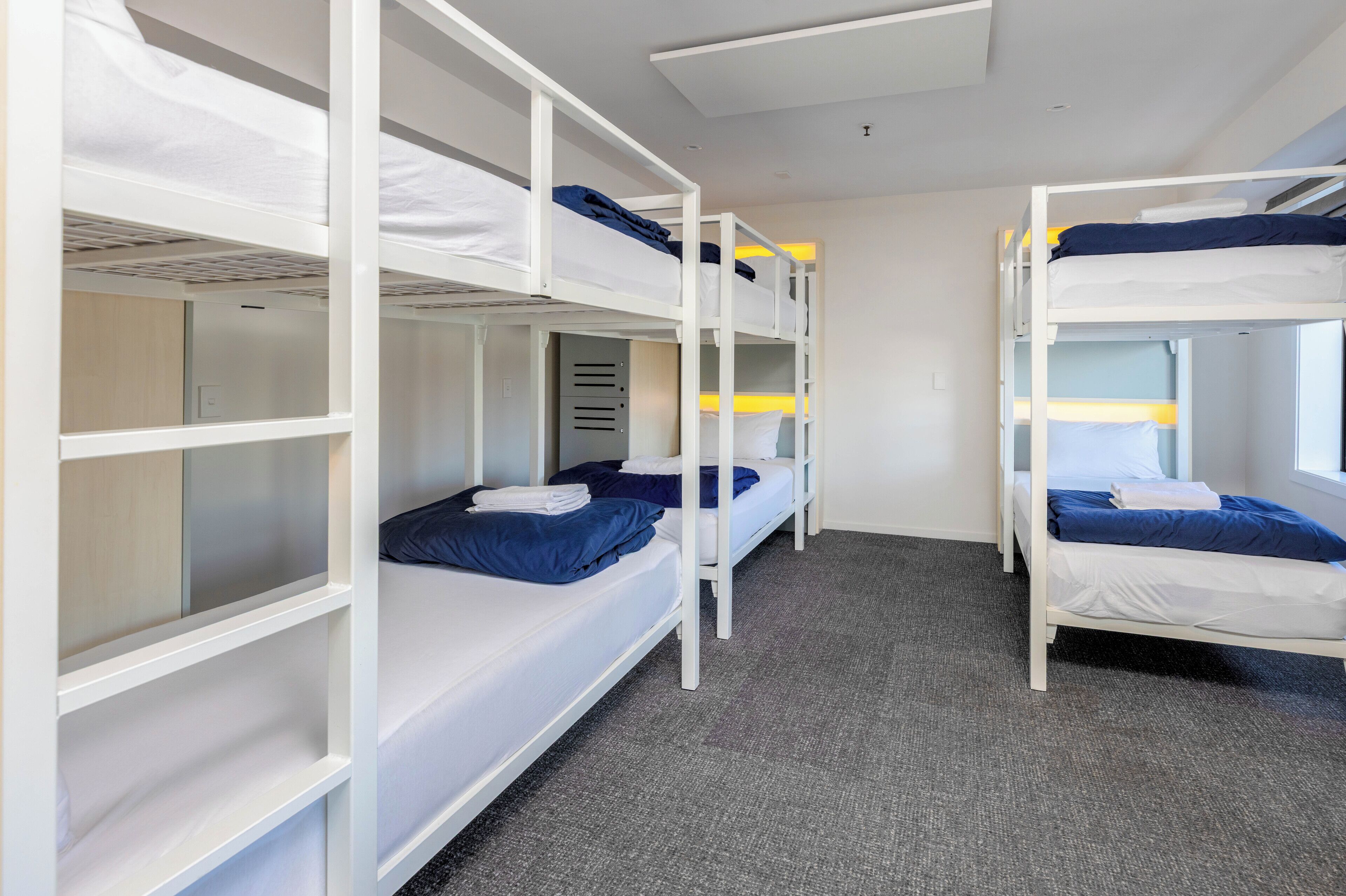 A room with bunk beds, carpeted floor, and a window.