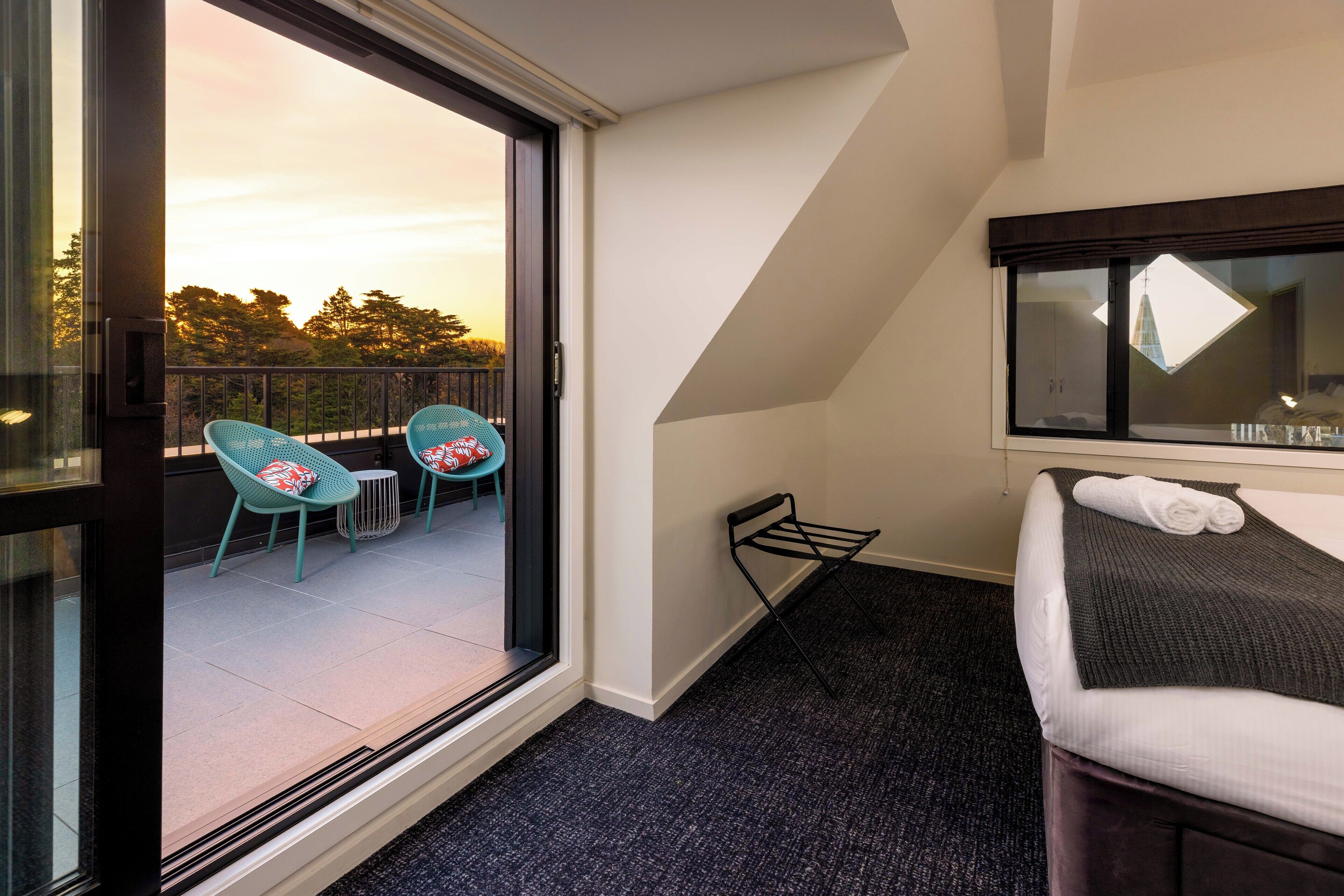 A hotel room with a balcony, a bed, and two chairs.