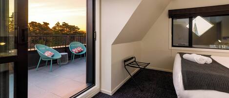 A hotel room with a balcony, a bed, and two chairs.