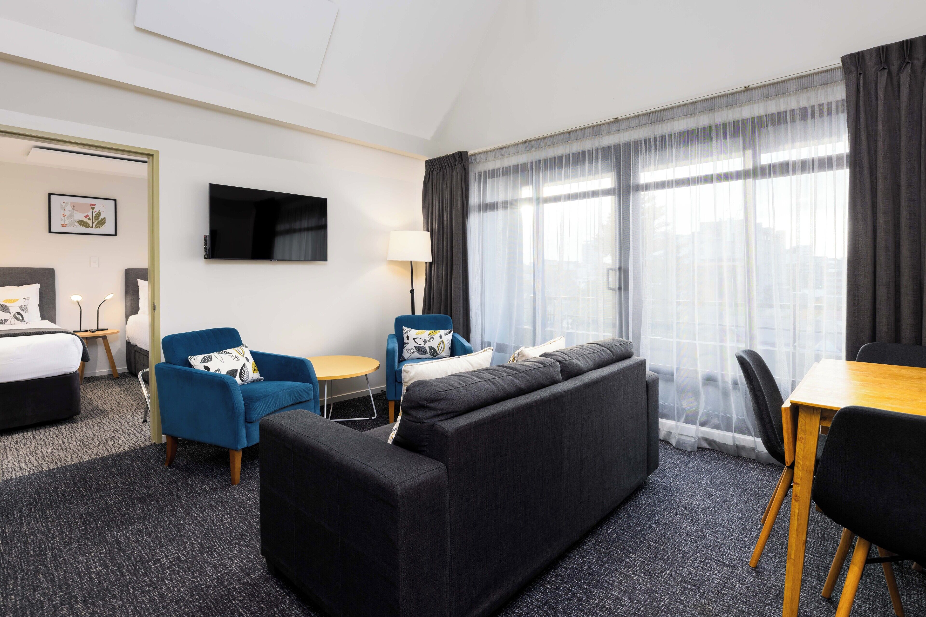 Una habitación de hotel moderna con una cama grande, un sofá, una mesa de comedor y un televisor.