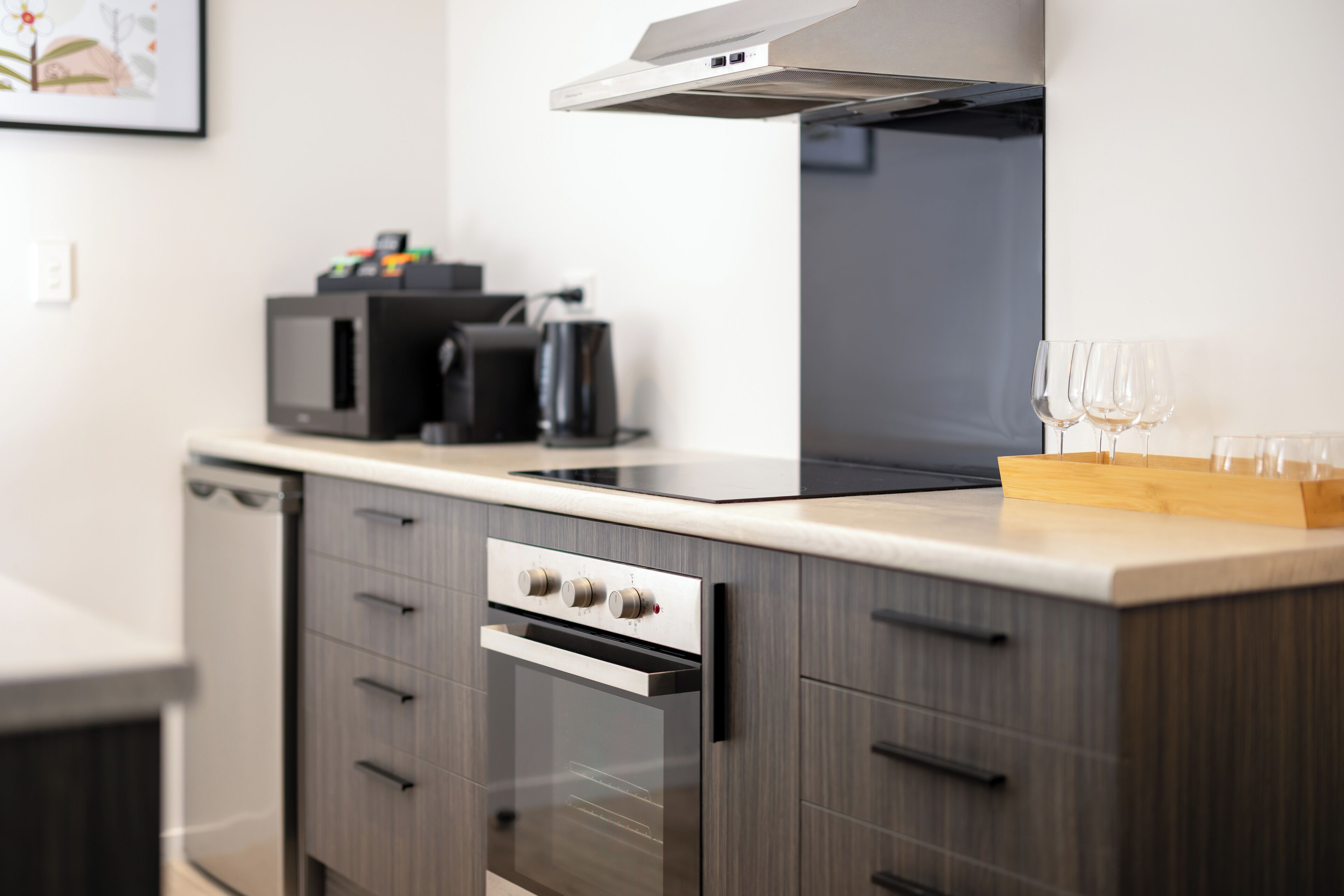 Una cocina moderna con horno integrado, microondas y campana extractora de acero inoxidable.