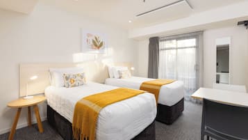 Ein Hotelzimmer mit zwei Betten, einem Schreibtisch und einem Spiegel.