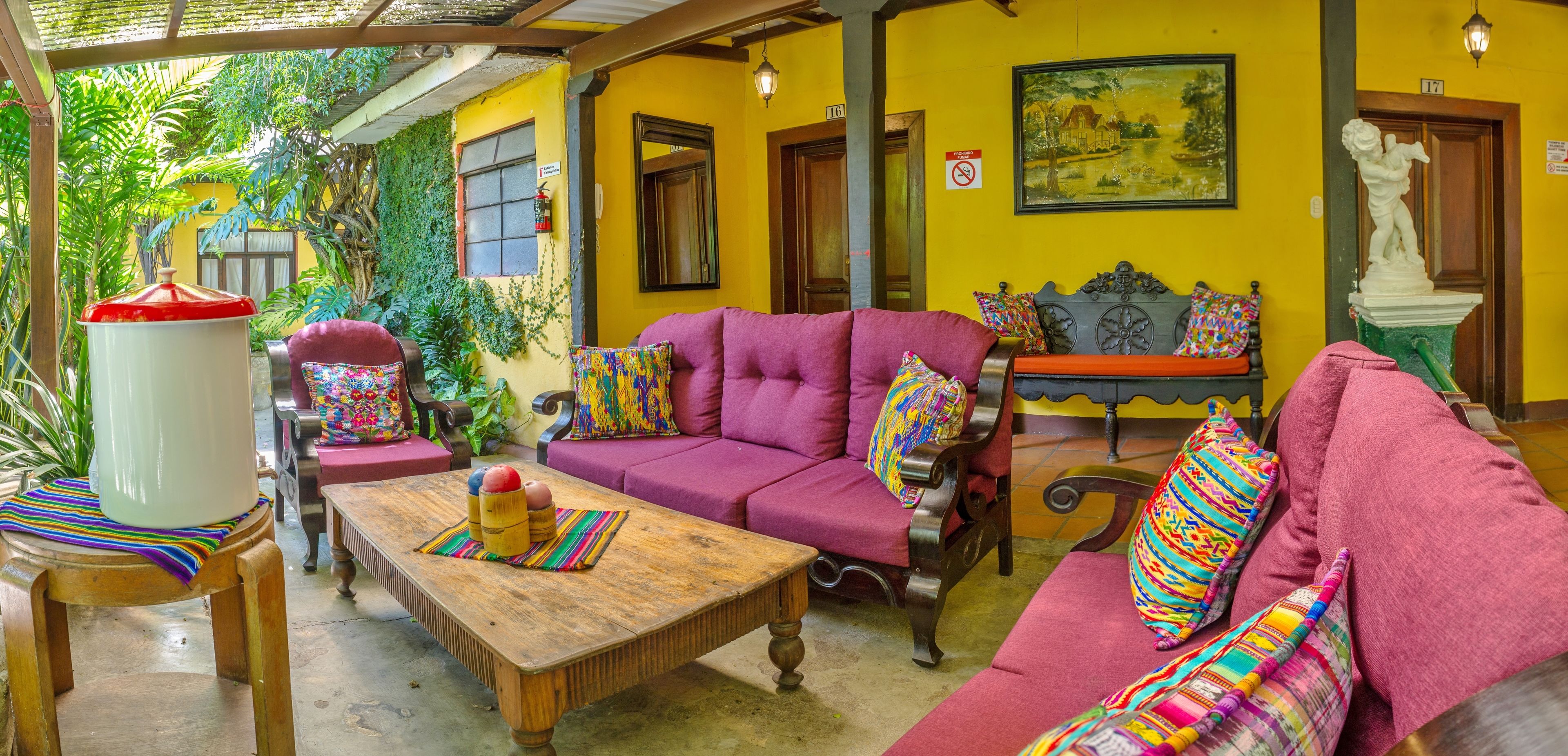 A cozy room with a wooden coffee table, a purple sofa, and a bench with colorful cushions.