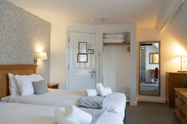 Habitación de hotel con dos camas, un armario, un espejo y una puerta con un aviso.