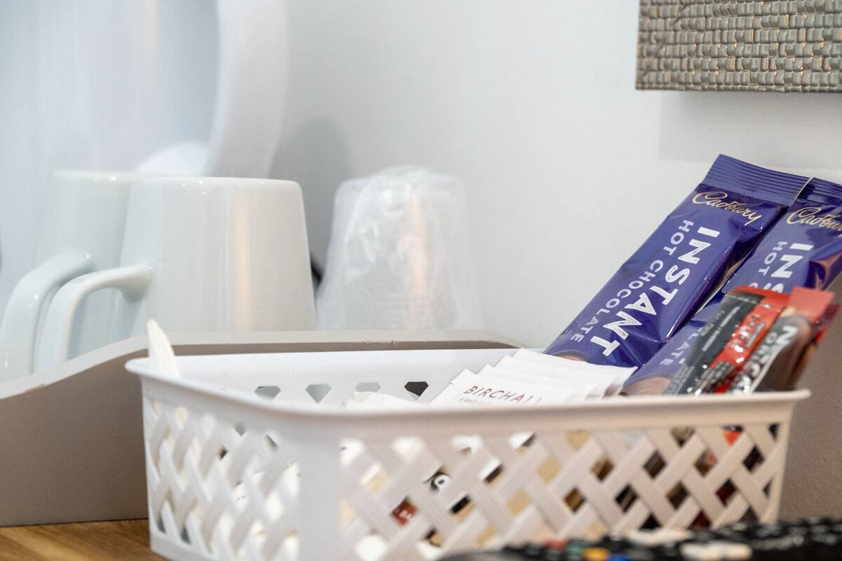 A white basket containing chocolate bars and a tissue box.
