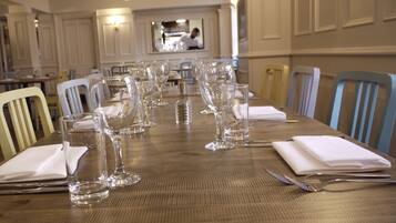 A dining table set with multiple wine glasses, napkins, and cutlery, with chairs around it.