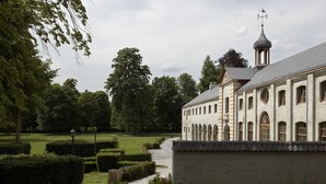 A historic building with arched windows and a tower with a weather vane. - B&B Baron's House Neerijse - Leuven (Huldenberg)