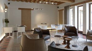 A spacious living area with modern furniture, a kitchen area, and large windows providing natural light. - B&B Baron's House Neerijse - Leuven (Huldenberg)