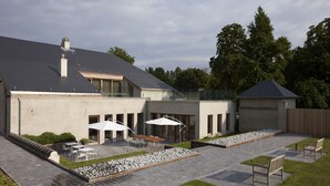 A modern house with a patio area featuring outdoor seating and a stone pathway. - B&B Baron's House Neerijse - Leuven (Huldenberg)