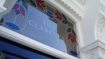A stained glass window with the inscription "THE CLARENCE" on a blue background.