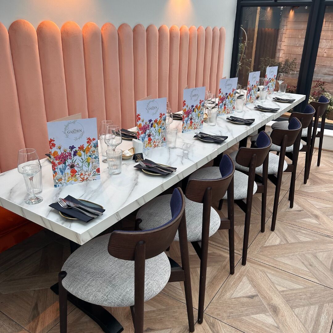 Mesa de jantar comprida com cadeiras, cada uma com um menu floral e copos.