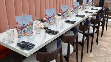 Mesa de jantar comprida com cadeiras, cada uma com um menu floral e copos.