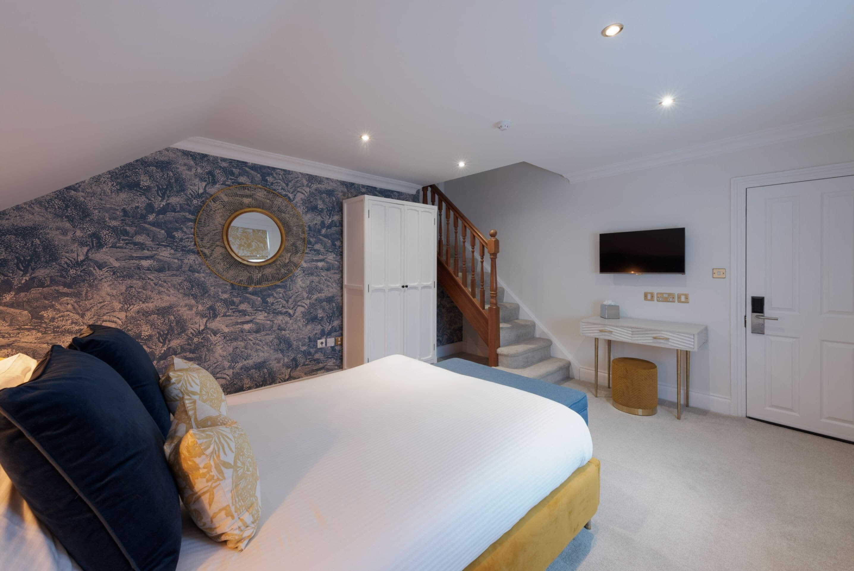 Ein Schlafzimmer mit einem Bett, einem Schminktisch, einem Fernseher und einer Treppe.