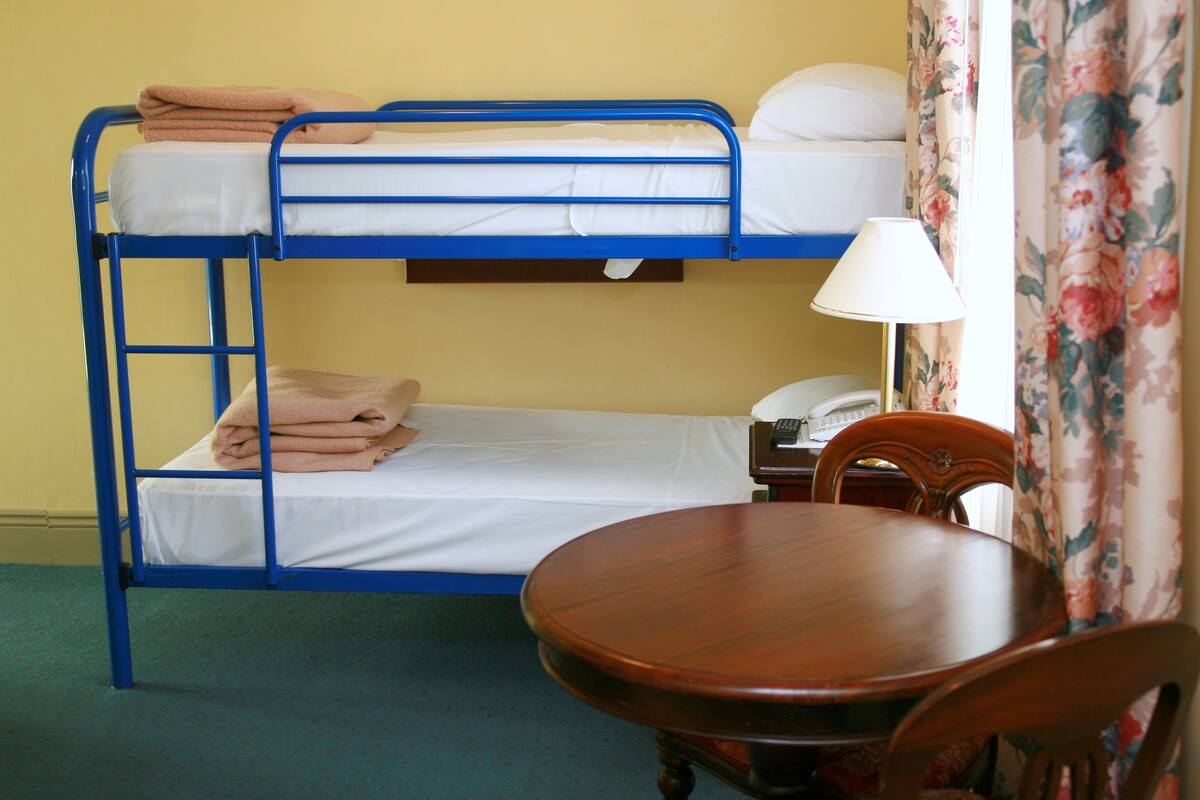 Una cama litera con una mesa y una silla en una habitación con cortinas de flores.