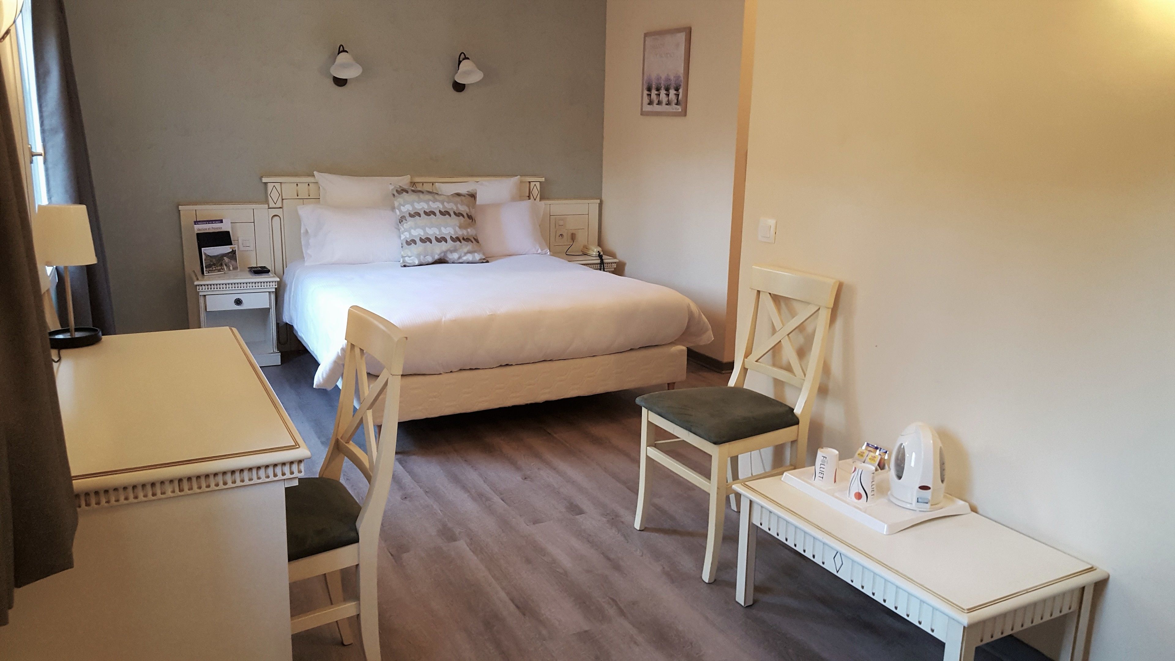 A neatly arranged hotel room with a bed, two bedside tables, a desk, and two chairs.