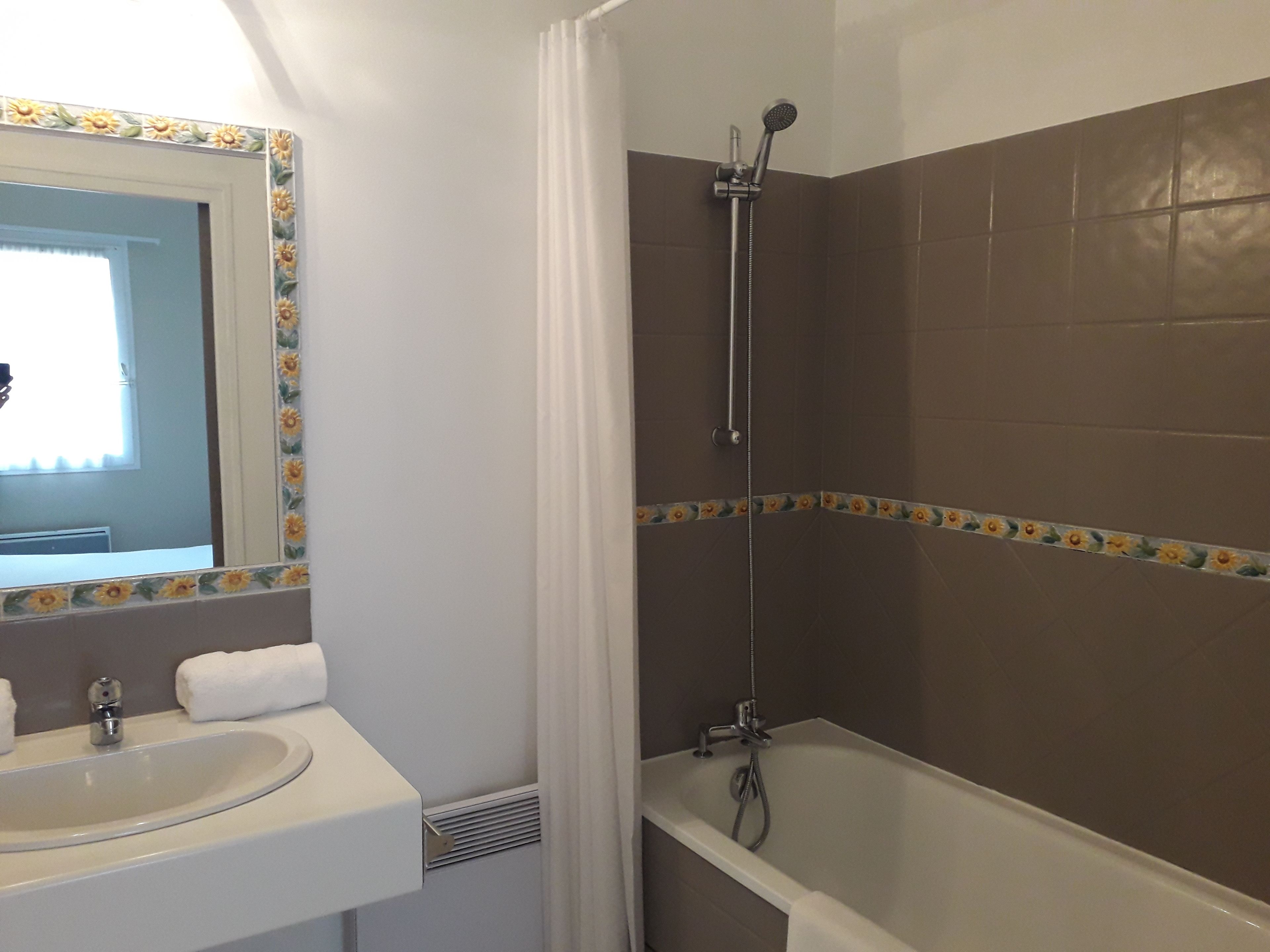 Un baño con lavamanos, espejo, ducha y bañera.