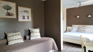 A bedroom with a bed, two pillows, a bedside table, and a wall-mounted lamp. - Le Mas du Colombier (Cadenet)