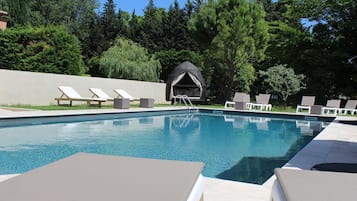 Relax by the serene pool surrounded by lush greenery and lounge chairs.
