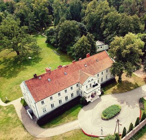 A large, historic building with a symmetrical facade, multiple windows, and a central entrance with a portico. - Dwor Kaliszki (Biala Piska)